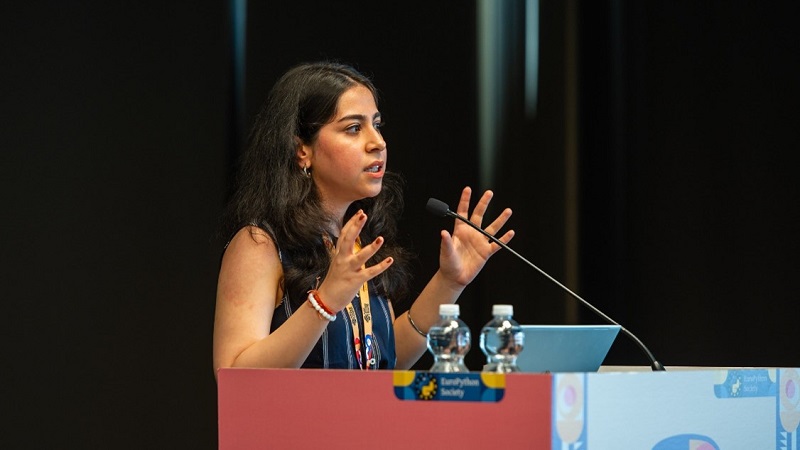 Ria speaking at a microphone