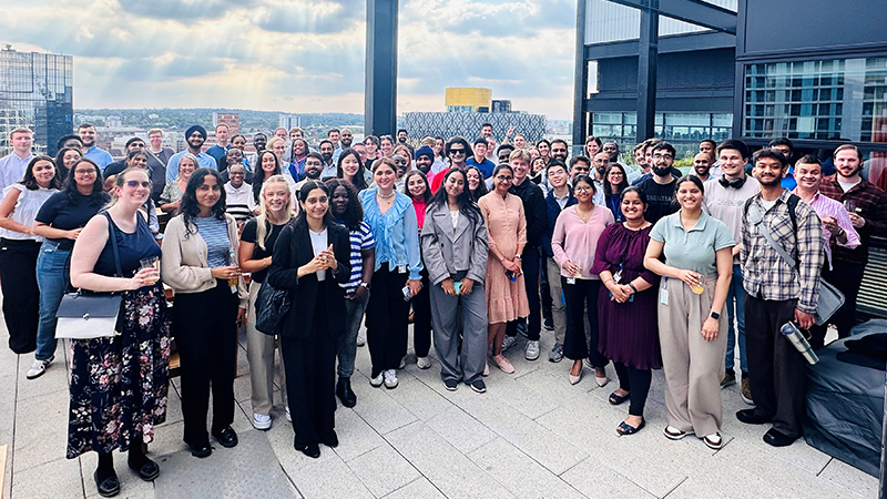 A group of colleagues standing on a rooftop posing for a group photo