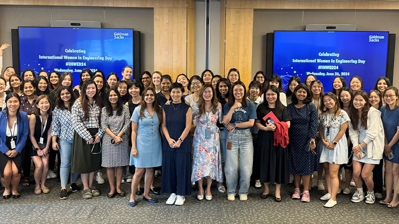 Colleagues stand in front of two blue screens posing for a group photo