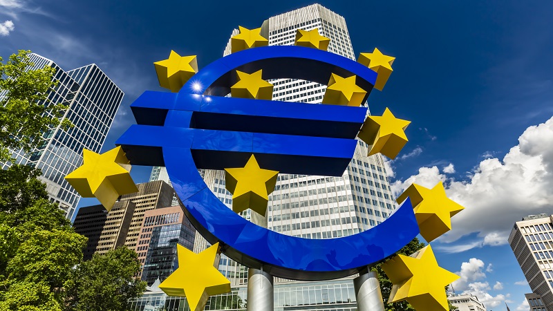 A statue depicting the euro currency symbol in front of tower blocks in Frankfurt.