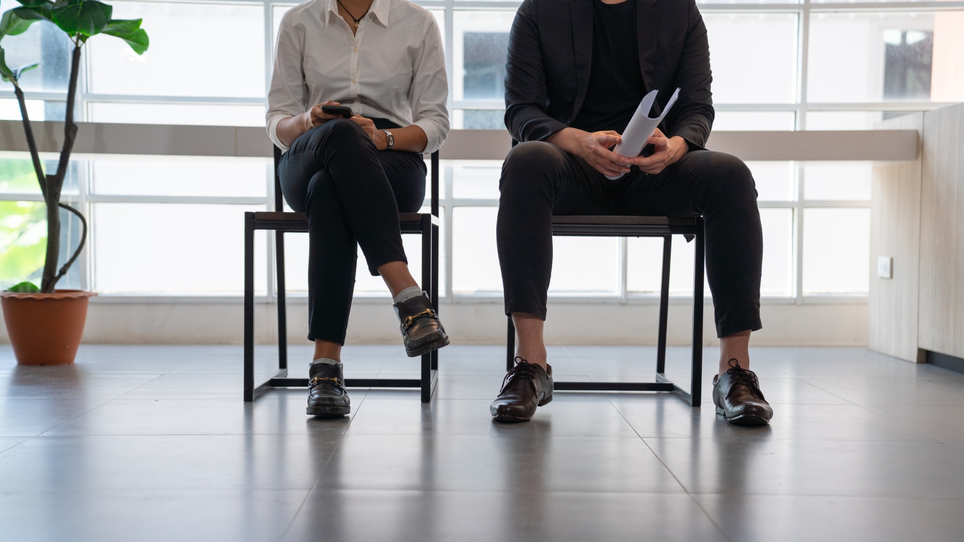Office workers sit on chairs in a corridor