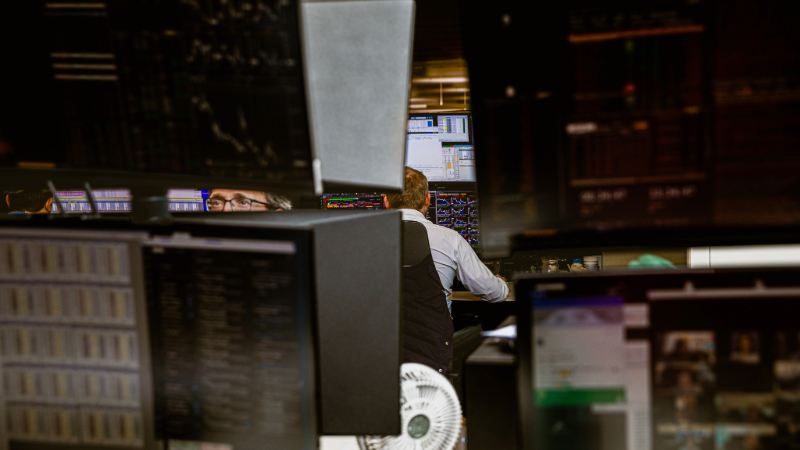 Photo of workers in finance industry surrounded by large computer screens