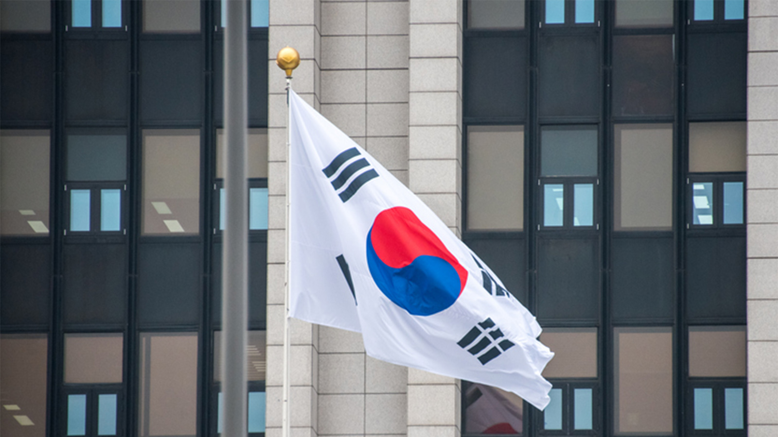 Photo of a South Korean flag in front of a building in Seoul.
