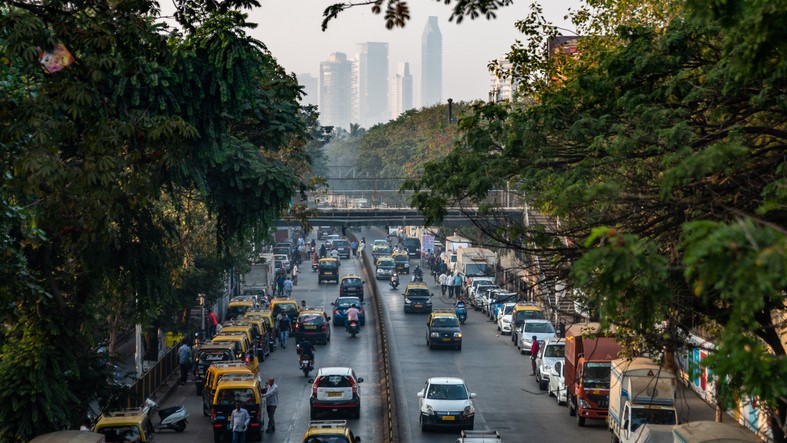 A Mumbai street with taxis and cars, and the city skyline in the distance
