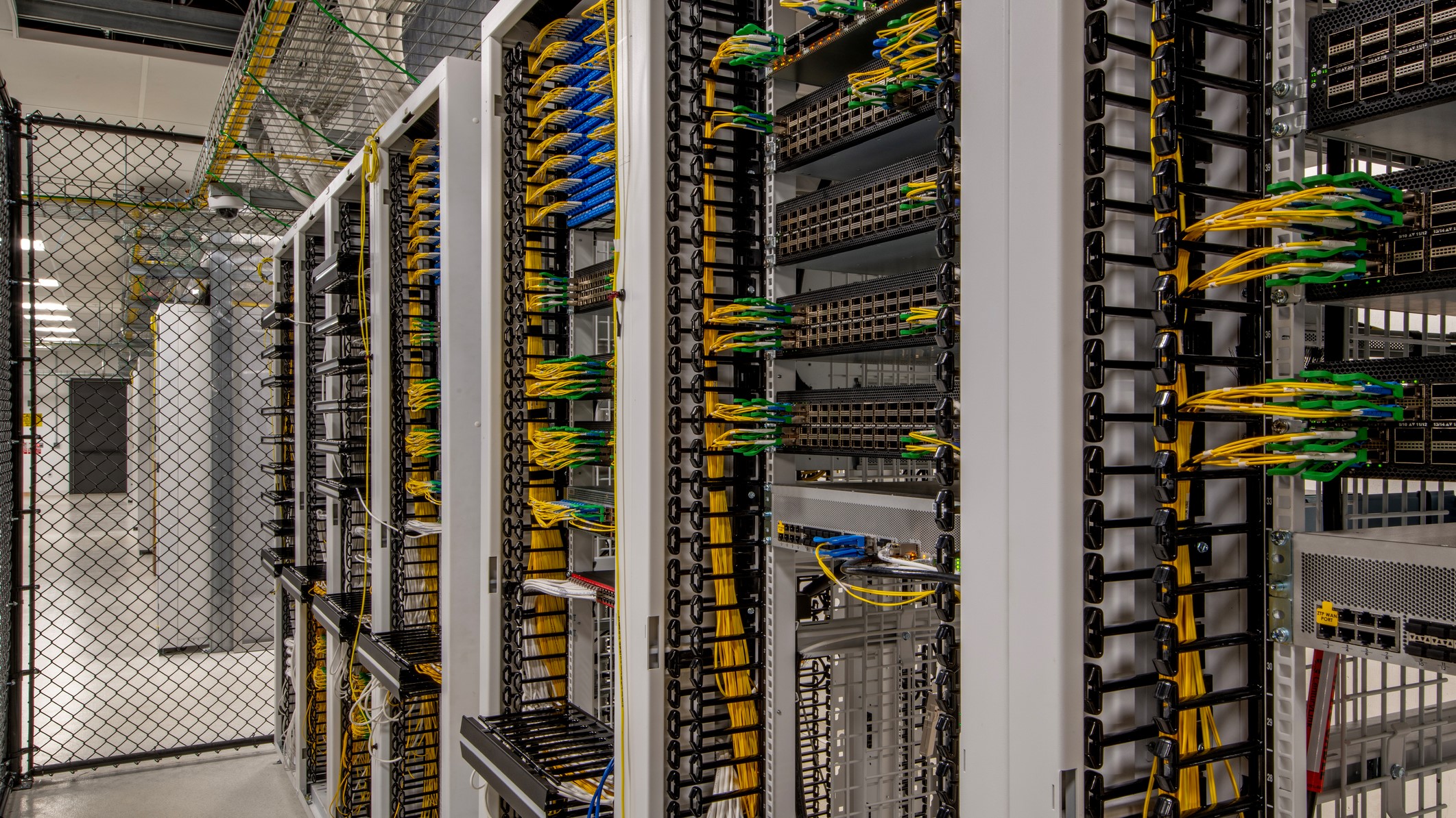 Photo of the interior of a data center with server racks and fiber optic connections